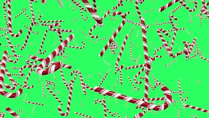 Red and white striped candy canes falling on an empty green background. Festive holiday pattern perfect for Christmas and New Year themes.