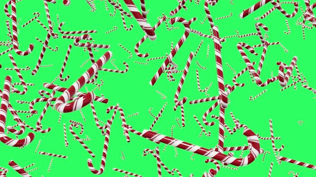 Red and white striped candy canes falling on an empty green background. Festive holiday pattern perfect for Christmas and New Year themes.
