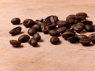 Roasted coffee beans scattered on wooden surface close up