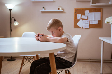 A boy with hearing aids engages with a smartphone, playing mobile games with focused enjoyment....