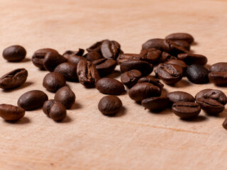 Roasted coffee beans scattered on wooden surface in close up macro view