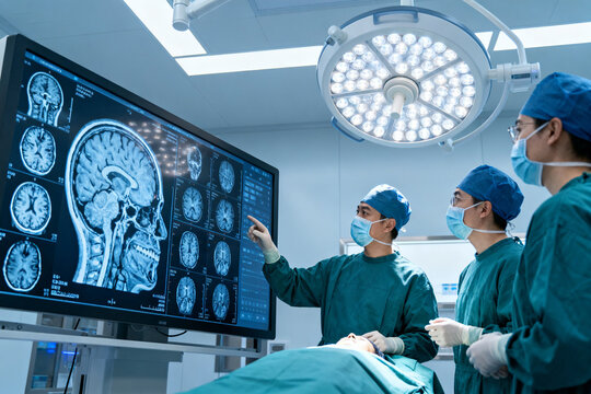 Surgeons reviewing brain MRI scans during a surgical procedure in an operating room - Powered by Adobe