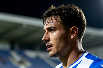 Close-up of a male athlete in a blue and white sports jersey during a nighttime game at a stadium.