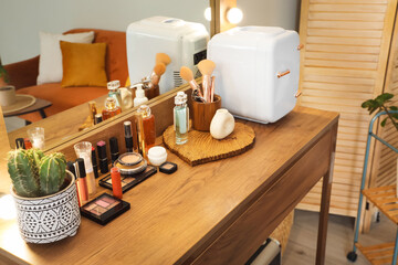Cosmetic refrigerator with makeup products on table in dressing room
