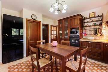 Kitchen with dining table, wooden melel, kitchen appliances and utensils.