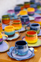 colorful ceramic cups on wooden table retale outdoors