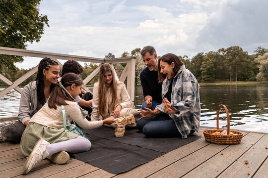 Multiethnic family group playing Jenga on lake pier