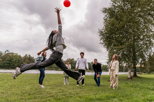 Group of people playing with a ball on a meadow in the park.