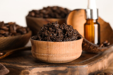 Composition with wooden tray and coffee body scrub in bowl on light background, closeup