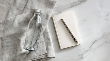 Minimalist Flat lay with Glass Bottle, White Notebook, and Pen on White Marble Background