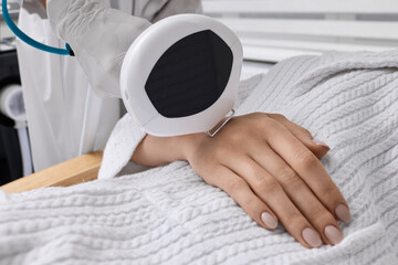 Removal of brown spots, freckles and rosacea on hands of female patient at cosmetology using machine with intense pulsed light IPL technology