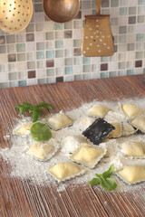 Homemade ravioli with basil leaves on wooden board in kitchen. Healthy eating and organic products. Traditional food, Italy. Brass cutlery. Vintage and old ladle and slotted spoon.