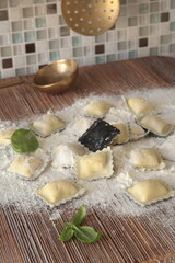 Homemade ravioli with basil leaves on wooden board. Healthy food and organic products.
