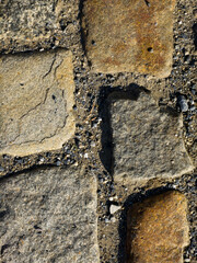 Close up of weathered cobblestone pavement with sand and gravel between stones