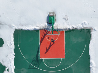 In winter, a boy was playing basketball on a basketball court
