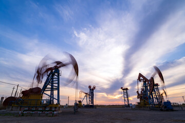 in the evening, oil pumps are running, The oil pump and the beautiful sunset reflected in the water, the silhouette of the beam pumping unit in the evening.