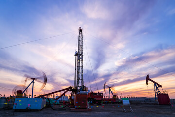 in the evening, oil pumps are running, The oil pump and the beautiful sunset reflected in the water, the silhouette of the beam pumping unit in the evening.