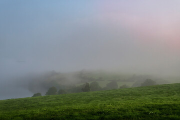 Misty Irish valley with lush green slopes, rolling hills, and foggy morning atmosphere.
