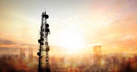 Telecommunication tower against sunset over cityscape. 