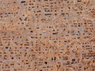 Close up of heavily rusted metal sheet with textured surface and geometric cutouts