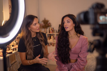 Two beauty influencers filming a cozy makeup tutorial with ring light and camera in a stylish vanity studio, candid conversation and glam content creation