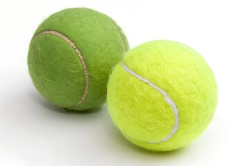 Two tennis balls side by side&mdash;one standard yellow-green, one dark green&mdash;with white curved seams on white background