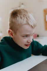 Naklejka premium A boy with hearing aids focuses intently while playing a game on his laptop, showcasing modern adaptive technology and inclusive digital entertainment for children with hearing disabilities