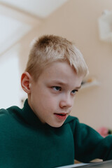 A boy with hearing aids focuses intently while playing a game on his laptop, showcasing modern adaptive technology and inclusive digital entertainment for children with hearing disabilities