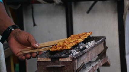 the process of grilling traditional Indonesian chicken satay