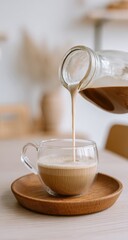 Fototapeta premium Creamy coffee being poured into a clear glass cup