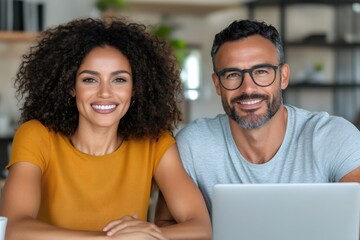 Happy multiracial couple smiling together using laptop at home