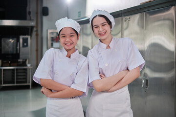Two kids in cooking class, Asian girl intern chef in white apron uniform with partner friend in...