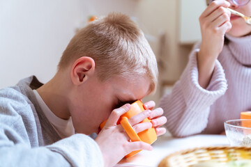 A boy with hearing aids and his mother share a warm conversation over tea in their cozy kitchen. A...