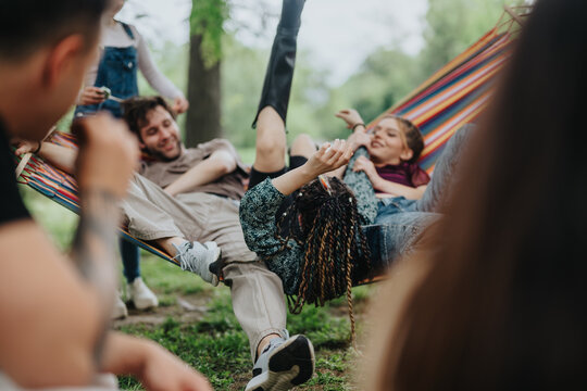A group of friends relaxes and has fun on a colorful hammock amid a natural park setting. Their cheerful expressions and carefree attitudes highlight the joy of shared moments in nature.
