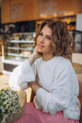 Portrait of a beautiful woman model with curly hair in a cafe at a table with flowers
