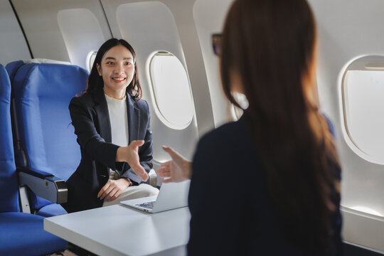 Businesswomen shaking hands during flight in private jet - Powered by Adobe