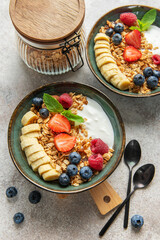 Healthy breakfast bowls with yogurt, granola, berries and banana slices