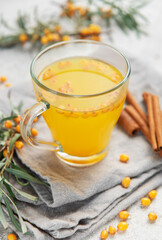Sea buckthorn tea with berries and cinnamon sticks on grey napkins