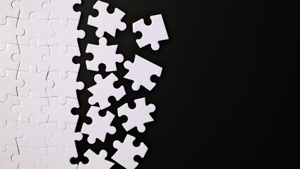 Unfinished white jigsaw puzzle pieces on black background