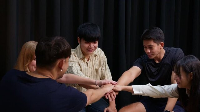 Group of people placing hands together in unity, symbolizing support, and trust during a psychotherapy group session