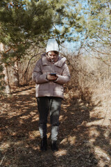 A young woman in a park uses her phone to navigate, enjoying nature while finding her way. Captures modern exploration, relaxation, and technology in daily life