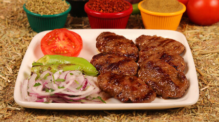 a serving of grilled meatballs with fresh vegetables on a white plate