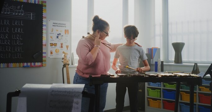 Primary School Boy Practicing Xylophone in Modern Music Class, Dreaming to Become Musician. Female Teacher Guiding Talented Student to Play Percussion Instrument. Rhythm Education, Music Training.