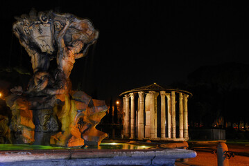 Temple of Hercules Victor ancient ruins and beautiful baroque Fountain of the Tritons lit up at night in Rome