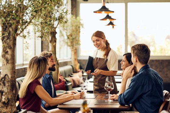 Diverse Group of Friends Dining in a Contemporary Restaurant With a Friendly Waitress