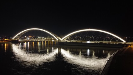 Naklejka premium Illuminated Modern Bridge Over the River at Night. Novi Sad, Serbia, 1.16.2024
