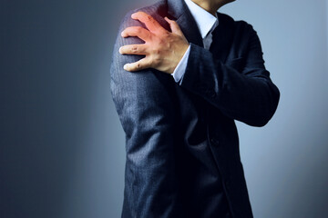 Office syndrome or work related illness concept with a man holding his shoulder and showing pain from tendon and nerve symptoms