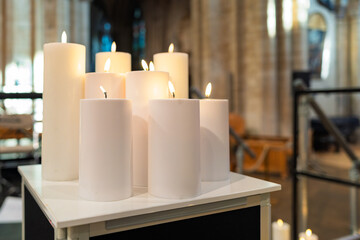 Group of LED candles seen lit during a musical concert with a famous cathedral in East Anglia, UK. The fake candles are positioned on a music amplifier.