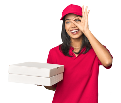 Latina delivering pizza, studio setup excited keeping ok gesture on eye.