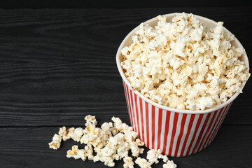 Classic red and white striped box filled with delicious, fluffy popcorn, 3D glasses on a black background.

